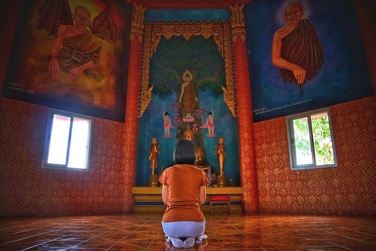 Rear view of woman praying in buddhist temple