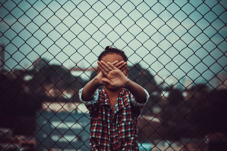 Portrait of girl standing by chainlink fence