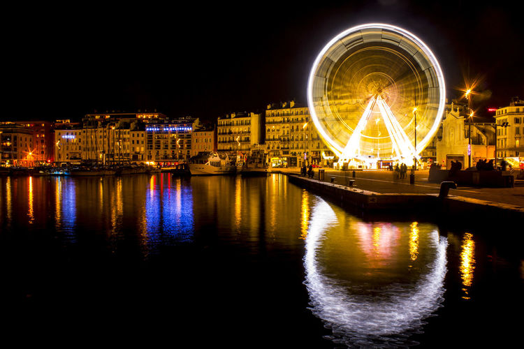 Illuminated ferris wheel by canal