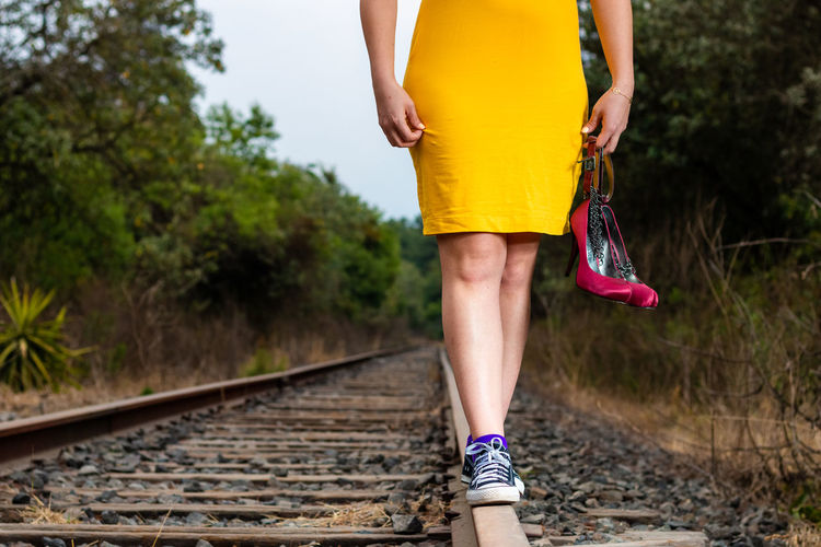 Low section of woman standing on railroad track