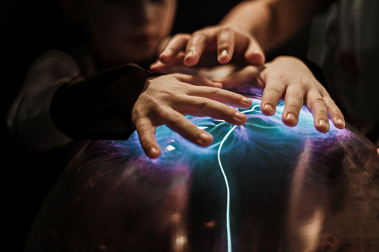 Close-up of people touching illuminated equipment