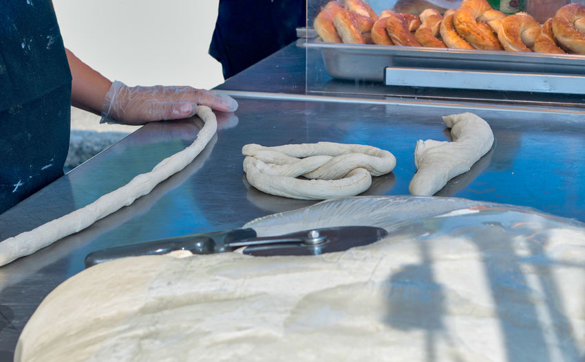 A baker rolls raw dough into a rope to make a hot, soft pretzel 