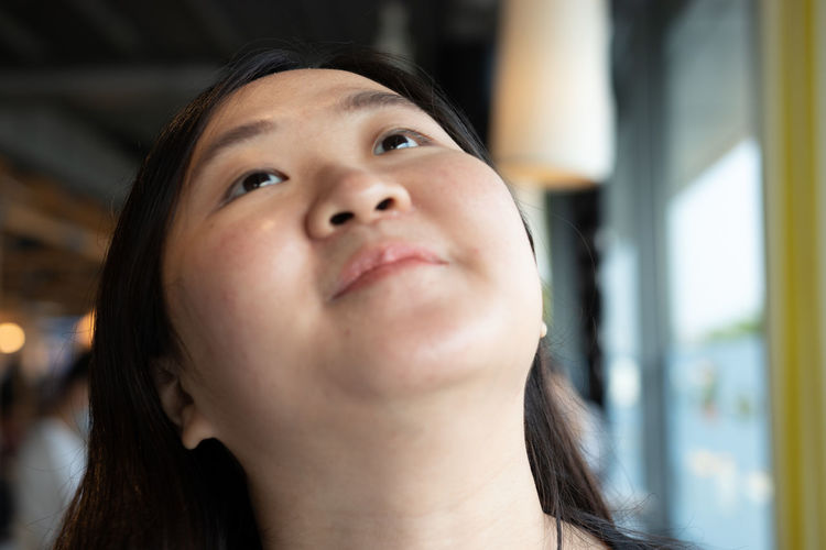Close-up portrait of smiling young woman looking up
