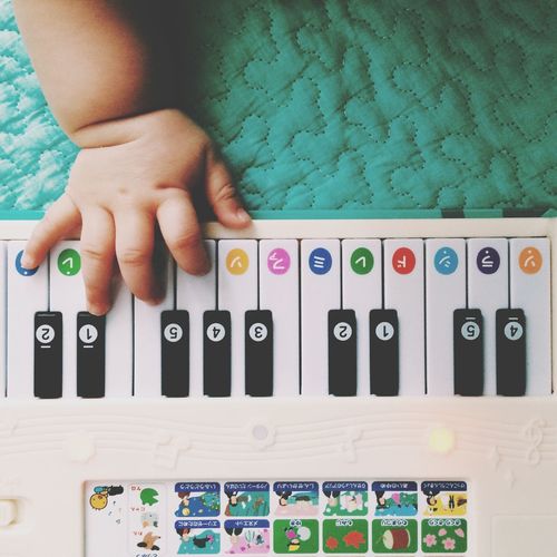 Cropped image of baby hand playing with toy piano