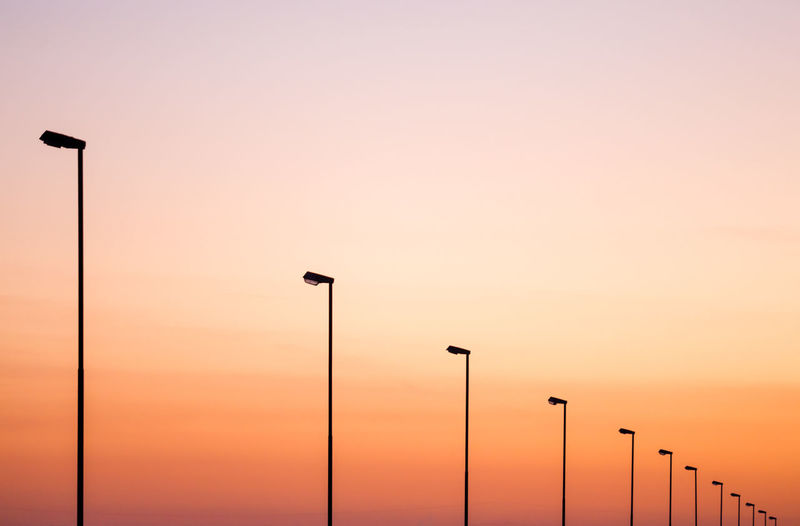 Low angle view of street lights against sky during sunset