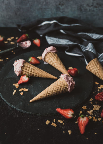 Close up of strawberry ice cream cones on a black background.