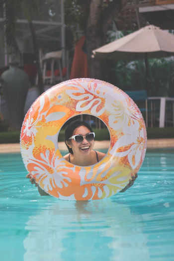 Cheerful woman holding inflatable ring in swimming pool