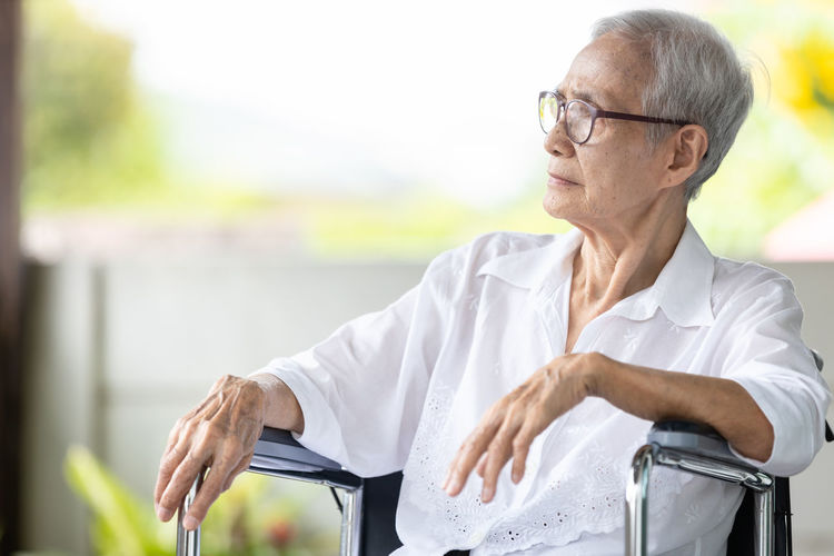 Senior woman looking away while sitting outdoors