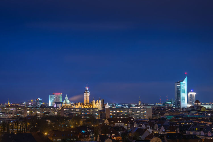 Illuminated buildings in city against blue sky