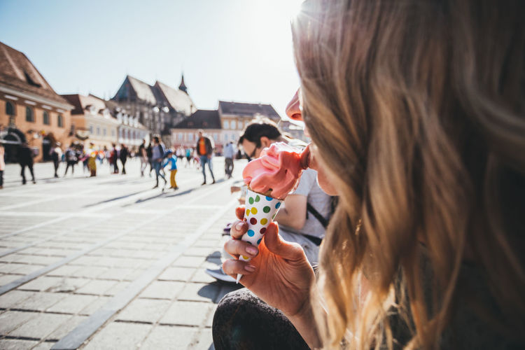 Woman licking ice cream in city