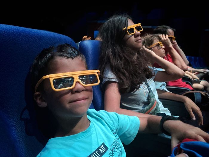 Family with yellow 3d glasses in a theater watching a movie- focus on young boy