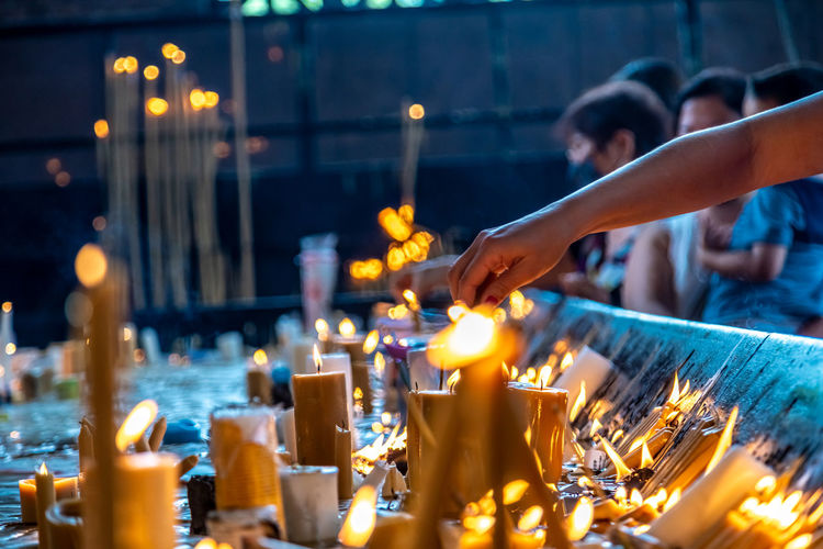 Cropped hand of woman holding lit candle