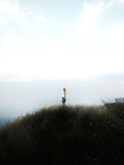 Young woman standing on mountain against clear sky