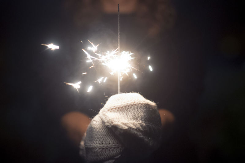 Rear view of woman holding sparkler at night