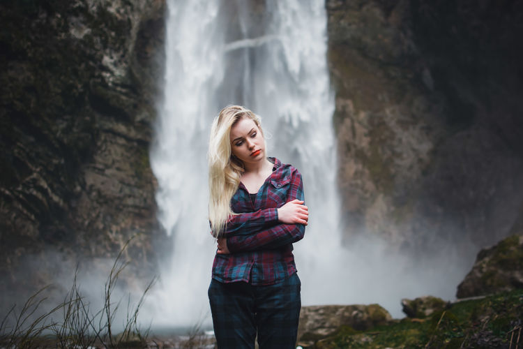 Woman standing against waterfall