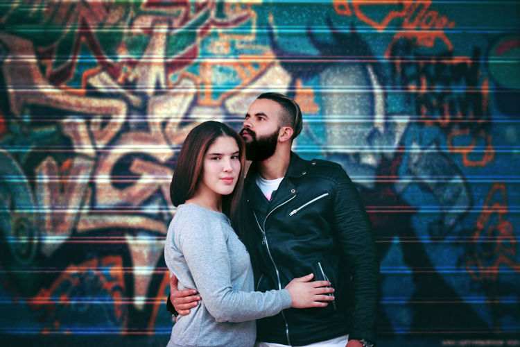 Couple standing against graffiti wall
