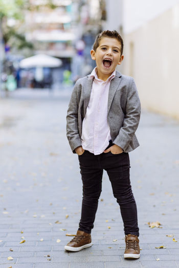 Portrait of happy boy shouting while standing on road