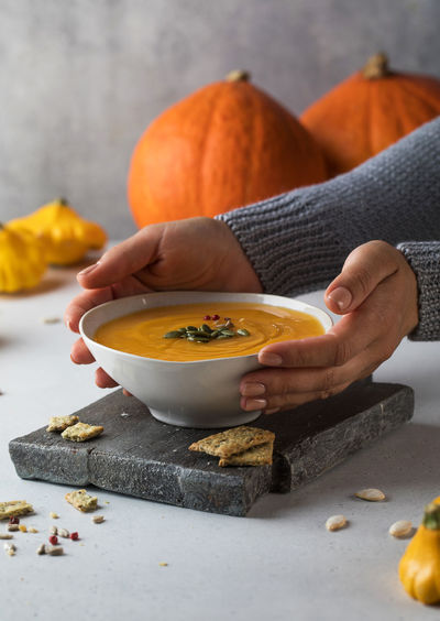 A bowl of warm pumpkin soup with seeds in your hands. comfortable riding. vegetarian dishes.