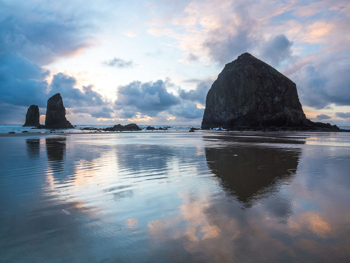 Scenic view of rock formation in sea against sky during sunset