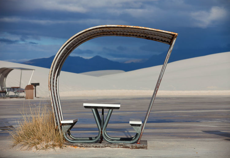 Empty picnic table and bench at white sands national monument against sky