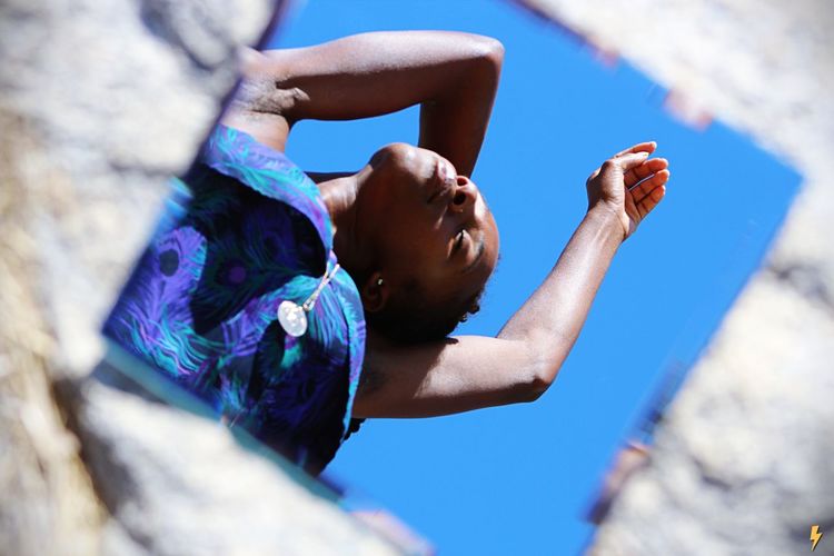 Low angle view of woman with arms raised against blue sky