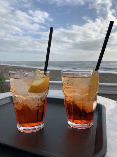 Close-up of drink in glasses on table against sea and sky