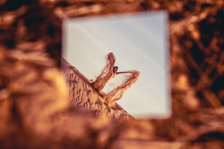 Reflection of woman spilling sand in mirror