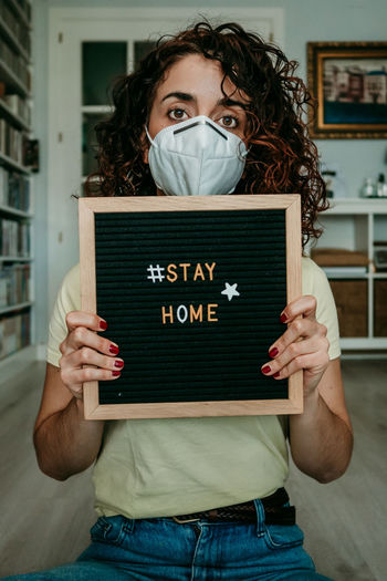 Portrait of woman holding slate with stay home text