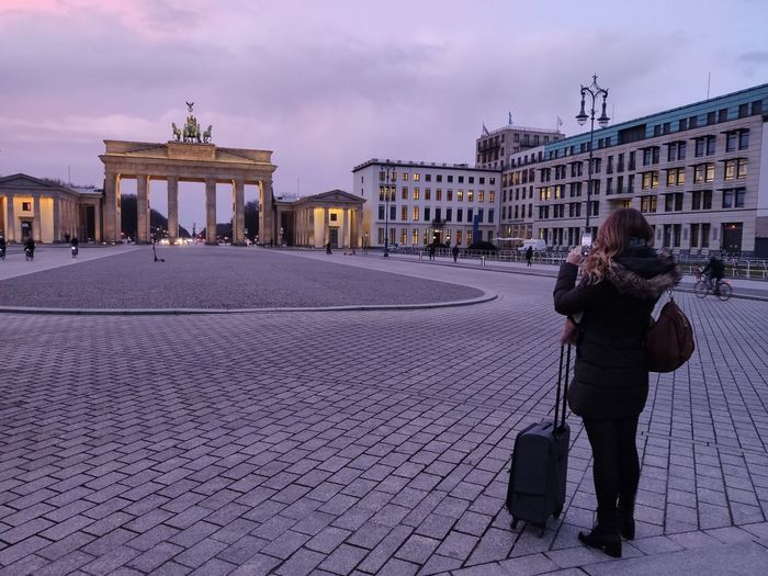 Side view of woman photographing brandenburg gate in city