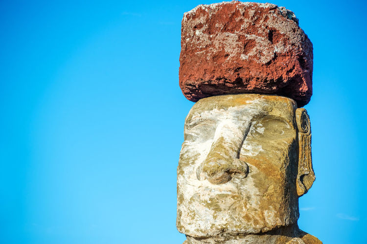 Close-up of moai at easter island against blue sky