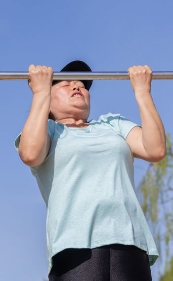 Low angle view of man holding hands against clear sky
