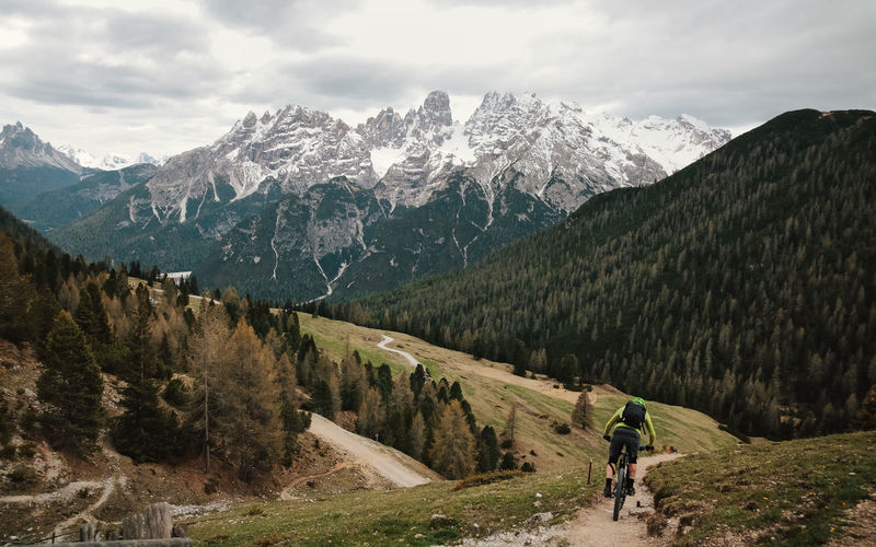 Rear view of man cycling on trail against sky