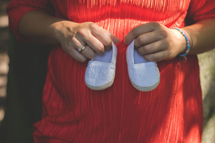 Midsection of pregnant woman holding baby booties
