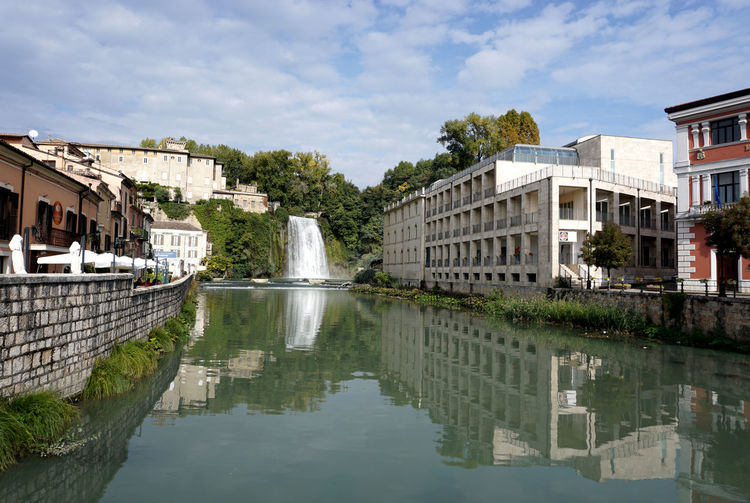 Buildings by lake against sky in city