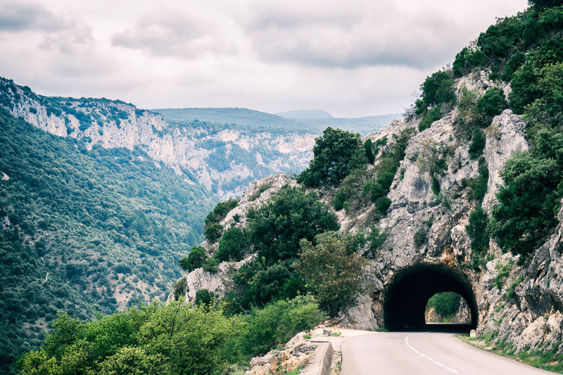 Mountain road with a small tunnel through rocks in the ardeche, france