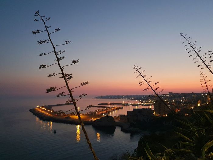 Silhouette sailboats by sea against sky during sunset