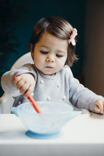 Portrait of cute baby girl in bowl on table