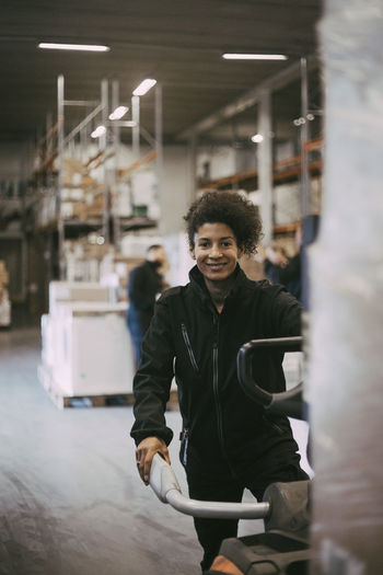Portrait of smiling female warehouse worker operating machinery