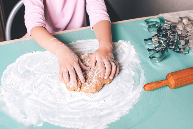 Closeup of child hands kneading fresh dough on the table for christmas gingerbread cookies 
