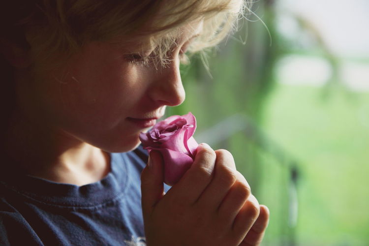 Close-up of boy smelling on rose