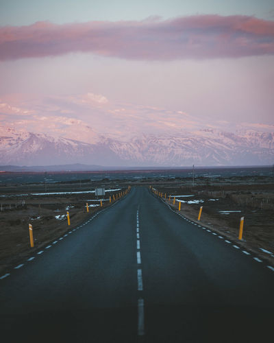 Road leading towards mountains against sky during sunset