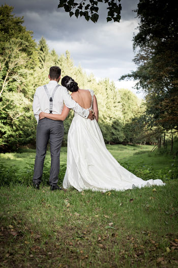 Rear view of bride and groom standing on grassy field
