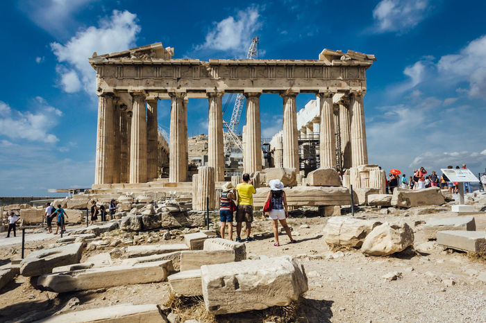 Tourists at parthenon ruins against sky