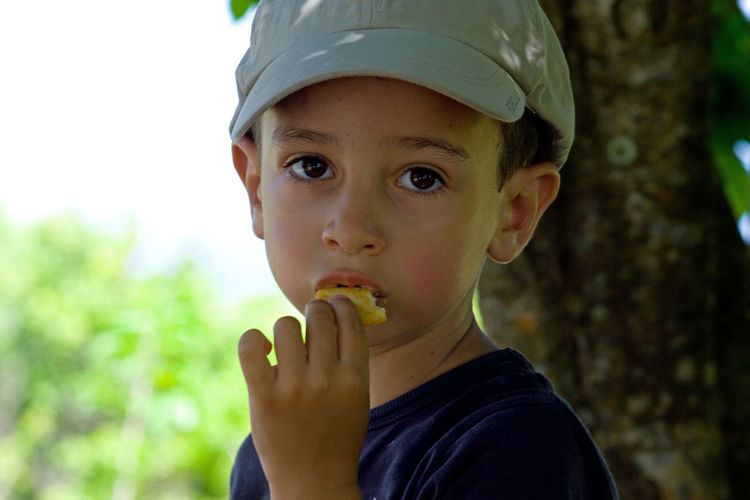 Portrait of boy in hat eating food
