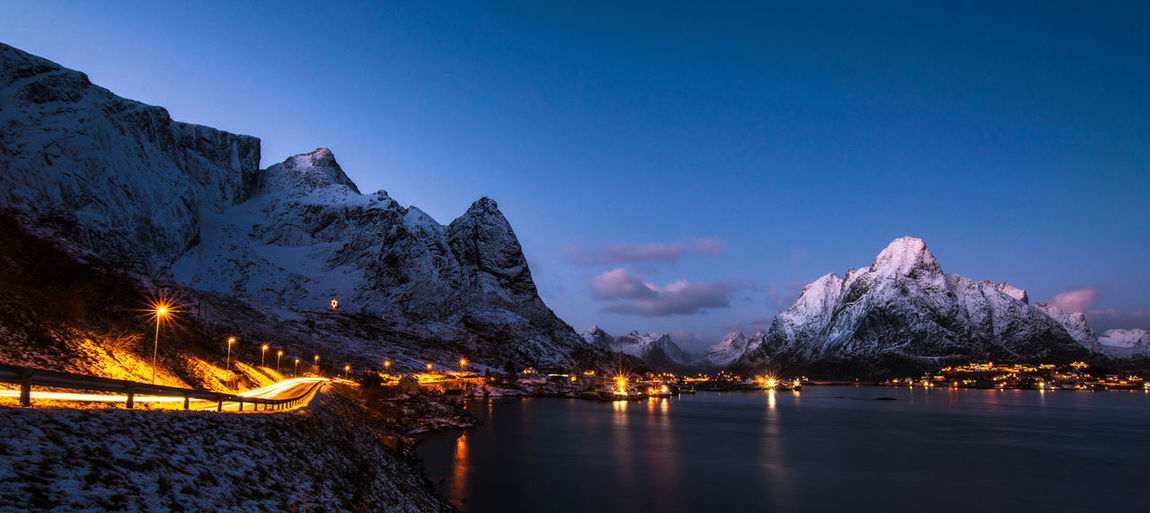 Scenic view of lake and mountains against blue sky at night