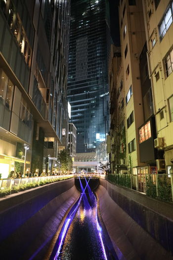Road amidst buildings in city at night