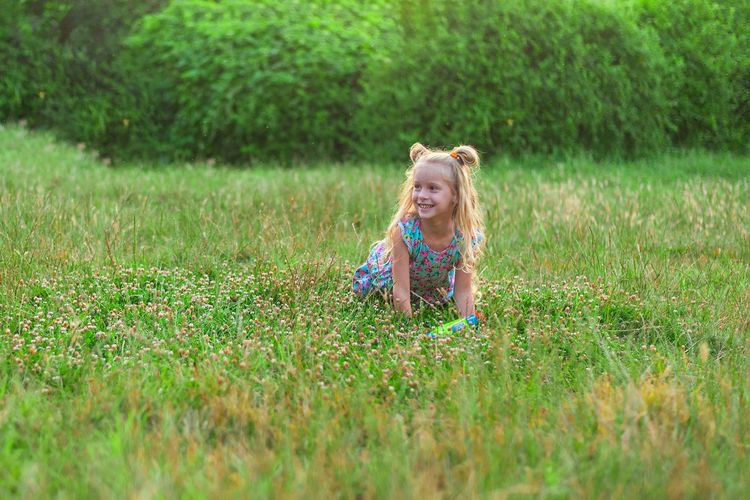 Little girls play in the summer on a green meadow with water pistols