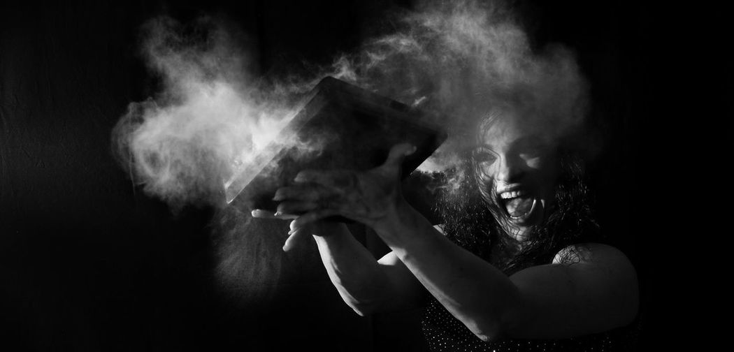 Woman playing with book against black background