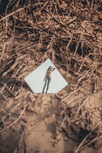 Reflection of woman in mirror standing against clear sky