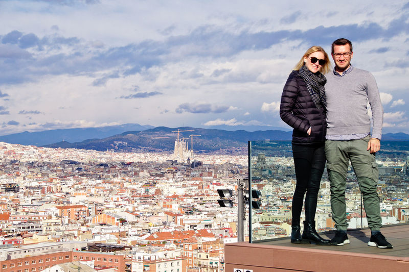 Full length of couple standing on balcony against cityscape